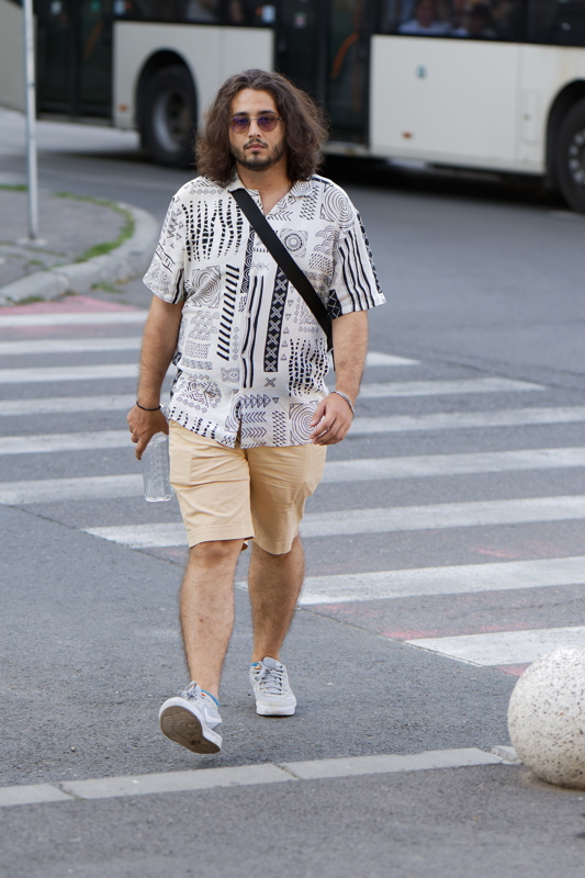 Person crossing the street in a patterned white short-sleeve shirt